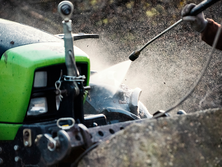 Pressure-washing green tractor fender