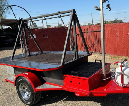 Red mobile barbecue trailer with hanging grill