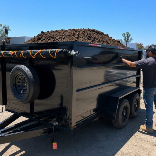 Black dump trailer piled with soil